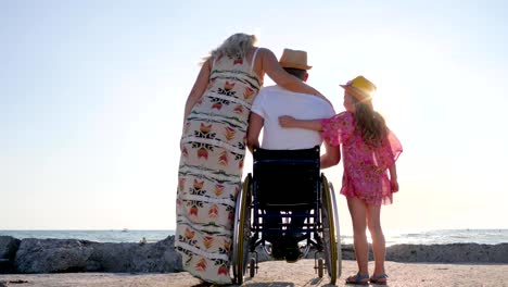 fin-de-semana-con-la-familia,-no-válido-con-embarazadas-mujer-y-niño-de-manos-de-subir,-cónyuge-en-silla-de-ruedas-abrazo-mujer-y-niña