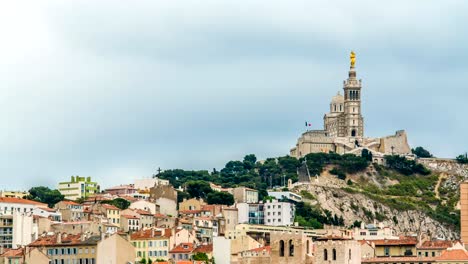 Grüne-Hügel-mit-Kirche-und-Häuser-am-Fuß,-goldene-Statue-am-Kirchturm