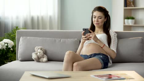 Mujer-esperando-en-el-sofá-escribiendo-la-mensaje-en-móvil,-social-networking