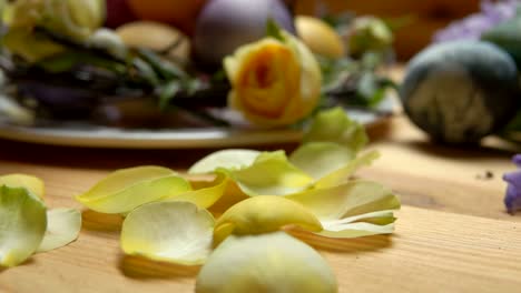 Petals-of-a-yellow-rose-fall-on-a-table-against-a-background-of-Easter-eggs