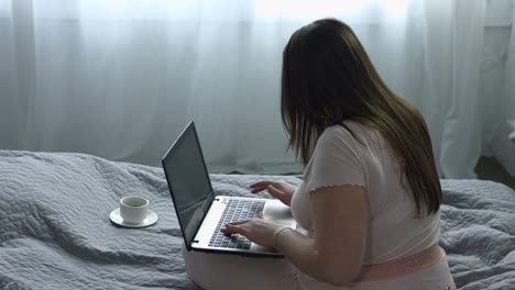 Attractive-woman-typing-on-laptop-on-the-bed