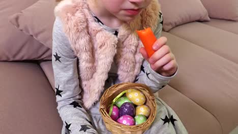 Niña-con-huevos-de-Pascua-decorativos-comer-zanahoria