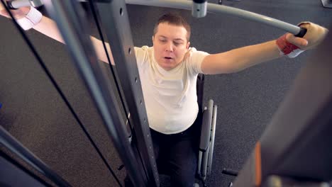 Athlete-in-a-wheelchair-strengthens-the-back-muscles-in-a-gym.