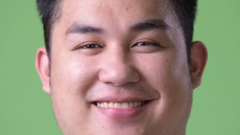 Young-handsome-overweight-Asian-man-against-green-background