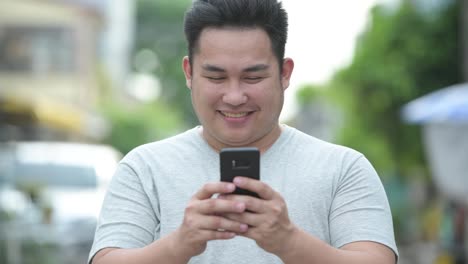 Young-handsome-overweight-Asian-man-in-the-streets-outdoors