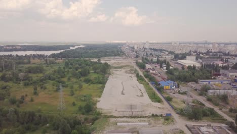 Construction-of-a-bypass-road-for-transport-near-the-outskirts-of-the-city.-Construction-site.-Aerial-view.-The-city's-line-with-nature-and-buildings