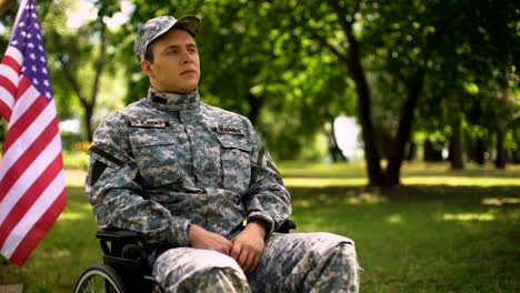 Veteran-saluting,-sitting-in-wheelchair,-waving-flag-behind,-independence-day