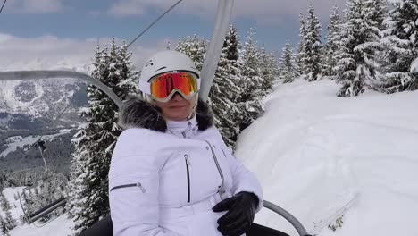 Happy-Skier-Climbs-Up-The-Chair-Lift-To-The-Mountain-Top-And-Shows-Her-Thumb-Up