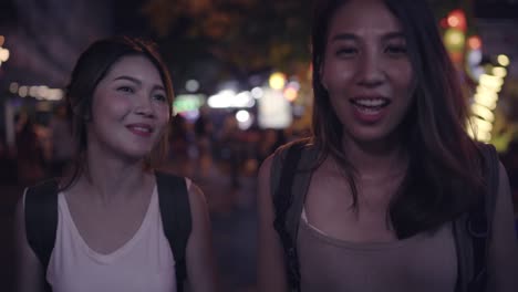 Traveler-backpacker-Asian-women-lesbian-lgbt-couple-travel-in-Bangkok,-Thailand.-Female-drinking-alcohol-or-beer-at-The-Khaosan-Road-the-most-famous-street-in-Bangkok.