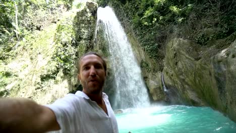 Young-man-taking-selfie-portrait-with-a-beautiful-waterfall