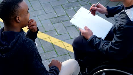 Two-disabled-athletics-discussing-over-clipboard-4k