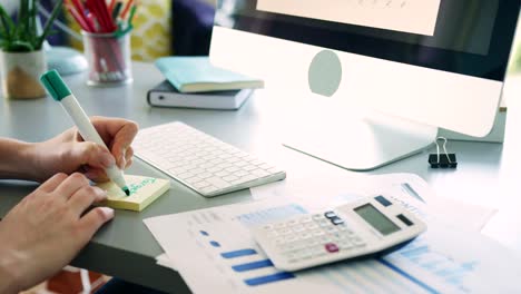 Woman-Writing-Post-It-Notes-At-Office-Desk