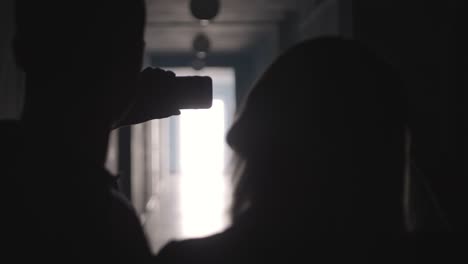 Silhouettes-of-Man-and-Woman-Taking-Selfie-with-Phone-in-Hallway