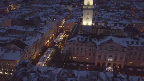 Lviv,-Ucrania---25-de-diciembre-de-2018.-Tiro-de-Arial.-Invierno.-Calle-plaza-Rynok.-Feria-de-Navidad.-Ayuntamiento-de-Lvov,-Consejo-de-la-ciudad.-Personas-están-caminando-en-el-centro-de-la-ciudad.-Adornos-navideños-y-luces.-Noche