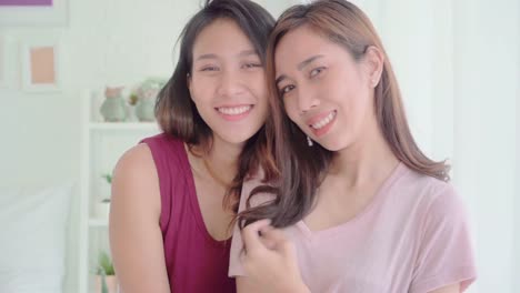 Young-Asian-women-lesbian-happy-couple-smiling-and-looking-to-camera-while-relax-in-her-bedroom-at-home.-Beautiful-female-using-relax-time-at-home.-Lifestyle-LGBT-couple-together-indoors-concept.