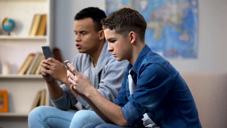 Adolescentes-multirraciales-jugando-juegos-en-smartphones,-ignorando-la-comunicación-en-vivo