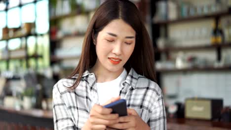 Glückliche-Frau-mit-Smartphone-in-einem-Café