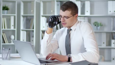 Hombre-de-negocios-con-brazo-protésico-hablando-por-teléfono-y-trabajo