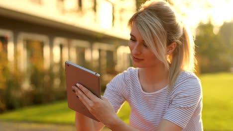 Young-female-student-using-tablet-computer-in-the-park.-Girl-doing-online-shopping-on-tablet-pc