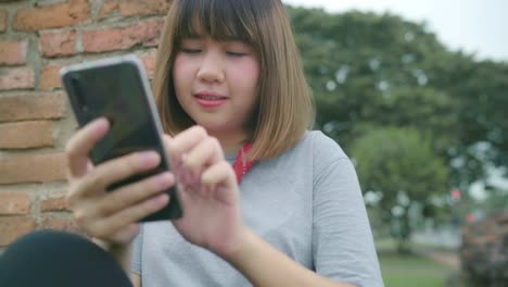 Traveler-Asian-woman-using-smartphone-checking-social-media-while-relax-after-spending-holiday-trip-at-Ayutthaya,-Thailand.