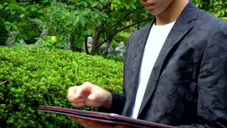 Young-Asian-Man-Using-Large-Tablet-Outdoors