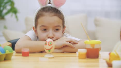 Tired-cute-girl-is-lying-down-the-table-and-watching-at-her-creation.-Colourised-funny-Easter-egg.