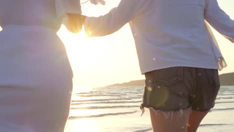 Slow-motion-pareja-de-jóvenes-lesbianas-asiáticas-corriendo-en-la-playa.-Hermosas-mujeres-amigas-feliz-relax-divertirse-en-la-playa-cerca-del-mar-cuando-la-puesta-de-sol-en-la-noche.-Lifestyle-pareja-lesbiana-viaje-en-concepto-de-playa.