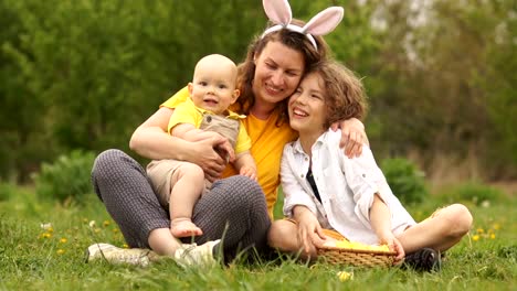 Encantadora-familia-abrazando-en-el-parque-en-un-picnic.-Feliz-familia-de-Pascua.-Mamá-y-dos-hijos.-Día-de-las-madres