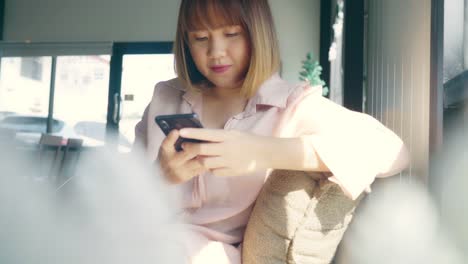 Geschäftspfreundin-Asiens,-die-Smartphone-zum-Sprechen,-Lesen-und-Texten-benutzen,-während-sie-im-Café-am-Tisch-sitzen.-Lifestyle-Smart-beautiful-Frauen-arbeiten-in-Coffeeshop-Konzepte.