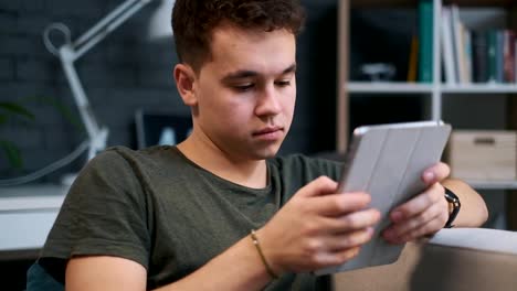 Porträtansicht-eines-hübschen-Teenager-Jungen,-der-auf-einem-Tablet-in-seinem-Zimmer-spielt