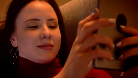 closeup-shoot-of-young-charming-caucasian-female-texting-on-the-tablet-and-smiling-while-lying-on-the-sofa-in-a-cozy-apartment-indoors