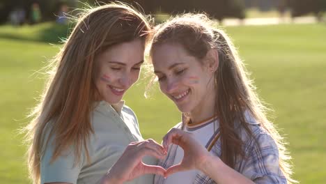 Retrato-de-lesbianas-sonrientes-mostrando-el-corazón-de-la-mano