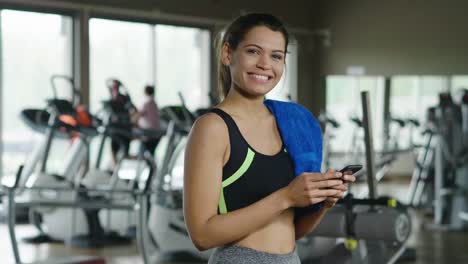 A-beautiful-young-woman-smiles-while-read-a-message,call-her-friends,-using-a-social-network-and-listen-to-the-music-at-the-gym.