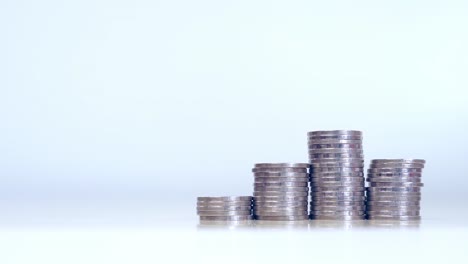 Stop-motion-increasing-and-decrease-pile-of-silver-coins-on-table-at-right-corner-with-white-color-background