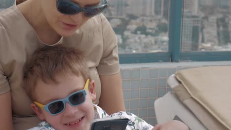 Niño-con-madre-relajándose-al-aire-libre-y-usando-el-teléfono-celular