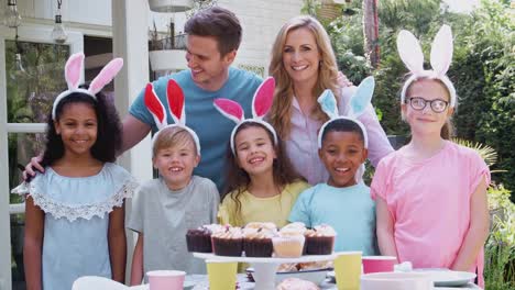 Retrato-de-niños-con-padres-con-orejas-de-conejo-de-pie-junto-a-la-mesa-al-aire-libre-disfrutando-de-la-fiesta-de-Pascua---rodado-a-cámara-lenta