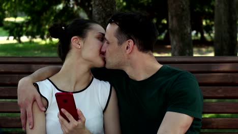 Young-lovers-kissing-sitting-on-a-park-bench.