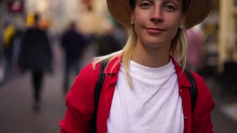 Portrait-of-blonde-authentic-caucasian-woman-traveler-standing-on-street-looking-at-camera