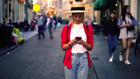 Positive-caucasian-woman-tourist-chatting-via-mobile-phone-connected-to-4G-internet-in-roaming,-millennial-female-typing-text-message-on-smartphone-on-street