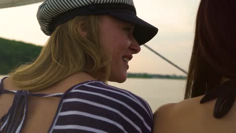 back-view-of-two-women-chatting-while-sailing-on-boat-at-sunset