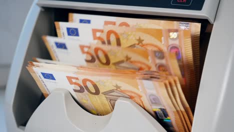 Orange-Euro-Banknoten-in-einem-Automaten-gezählt.