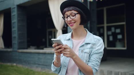 Fröhliche-Mädchen-mit-Smartphone-im-Freien-lächelnd-berührenden-Bildschirm-genießen-Gerät