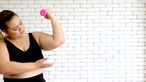 large-build-young-woman-in-sportswear-exercising-with-dumbball-at-home