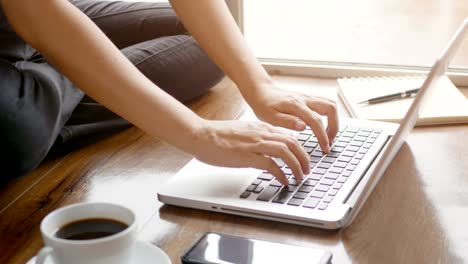 4K.-woman-hand-typing-on-notebook-computer-laptop-keyboard-for-working-on-the-floor-at-home-with-relaxing