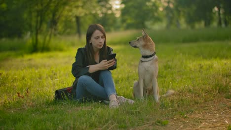 Das-Mädchen-überprüft-ihre-sozialen-Netzwerke-in-einem-Smartphone-neben-dem-Hund