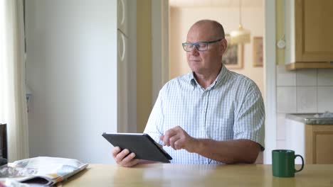 Glücklicher-Senior-Mann-mit-digitalen-Tablet-in-der-Nähe-des-Fensters