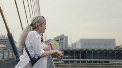 Parejas-lesbianas-asiáticas-jugando-burbujas-de-jabón-mientras-están-de-pie-en-el-puente.