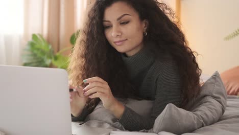 Frau-mit-Laptop-und-Schreiben-von-Notizen-im-Bett