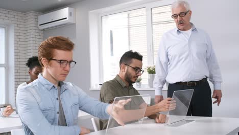 Estudiantes-universitarios-que-trabajan-en-tabletas-interactivas-y-verificación-de-maestros