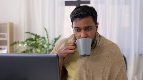 healthcare,-technology-and-people-concept---sick-indian-man-in-blanket-with-sore-throat-having-video-call-on-laptop-computer-at-home